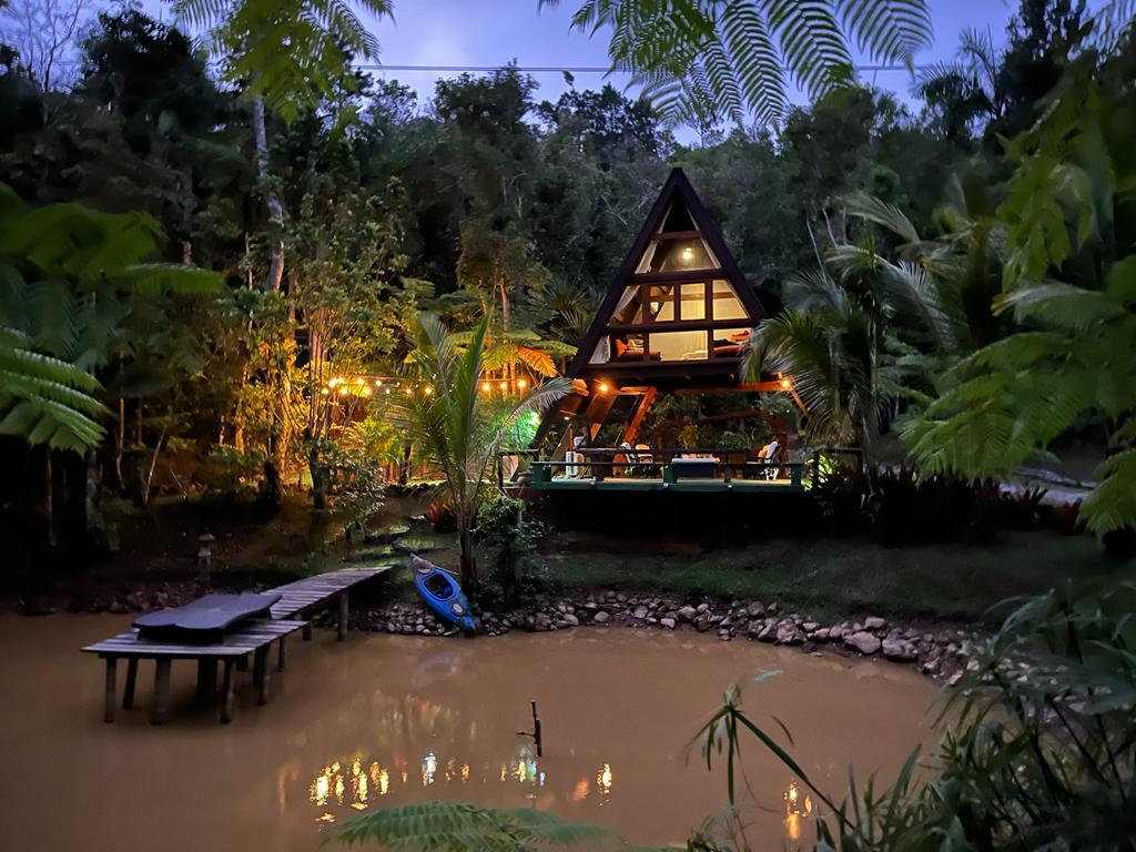 La cabaña Grand Bali iluminada al atardecer, reflejada en el estanque